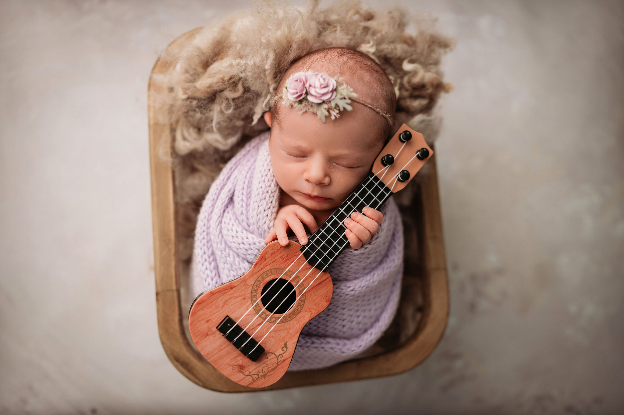 newborn photographer photographs beautiful newborn baby girl holding a tiny guitar